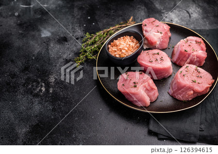 Tender fresh pork medallion, raw tenderloin meat perfect for elevating your dinner table with a touch of culinary finesse. black background. top view 126394615