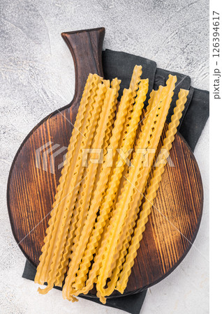 Delicate raw mafaldine pasta noodles, perfect for tossing with fresh ingredients and savory sauces. white background. top view 126394617