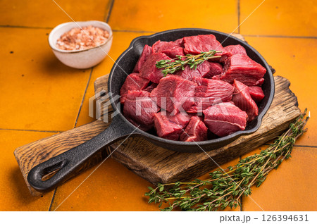 Ready for cooking Diced Elk meat, raw Game Meat in a pan. orange background. top view Ready for cooking Diced Elk meat, raw Game Meat in a pan. orange background. top view 126394631
