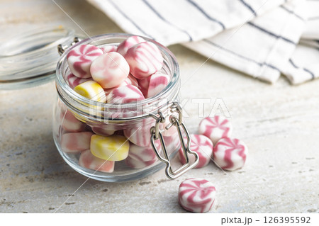 Colorful striped candies in jar on kitchen table. Colorful striped candies in jar on kitchen table. 126395592