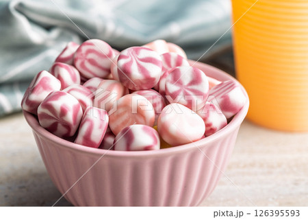 Colorful striped candies in bowl on kitchen table. Colorful striped candies in bowl on kitchen table. 126395593