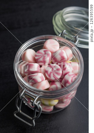 Colorful striped candies in jar on black table. Colorful striped candies in jar on black table. 126395599