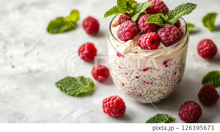 A jar of creamy chia pudding topped with fresh raspberries and mint leaves, placed on a clean white table with soft natural light, concept of healthy eating A jar of creamy chia pudding topped with fresh raspberries and mint leaves, placed on a clean white table with soft natural light, concept of healthy eating 126395671