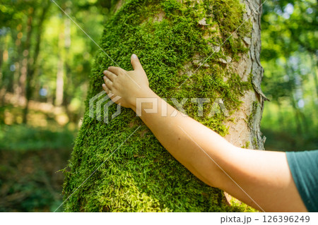 Woman’s Hand Touching Mossy Tree Trunk in Forest 126396249