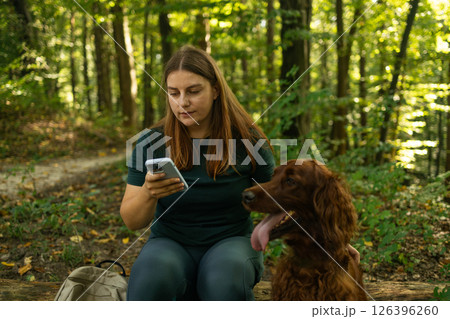Woman Sitting on a Log with Her Dog in the Forest 126396260
