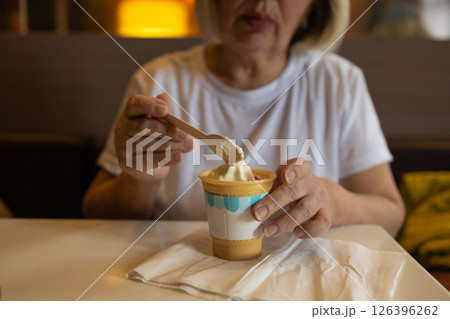 Senior woman eating ice cream with wooden spoon, eco-friendly, sustainable choices 126396262