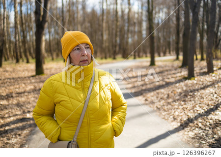 Woman in Yellow Jacket and Hat Standing on Park Path in Autumn 126396267
