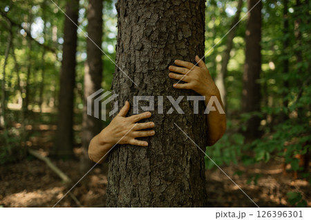 Person Hugging Tree with Open Hands in Forest Showing Deep Connection to Nature and Earth 126396301