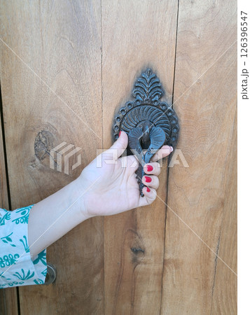 Woman hand holding a vintage doorknob on wooden door 126396547
