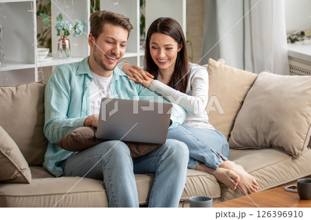 Couple laughing while browsing laptop together Couple laughing while browsing laptop together 126396910