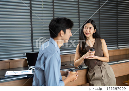 Business Conversation and Collaboration. Young professionals sharing ideas over coffee in a modern office. 126397099