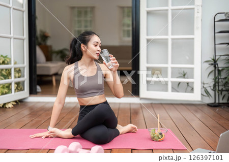 Yoga and Wellness. Young woman enjoying hydration and healthy eating during yoga practice at home. 126397101