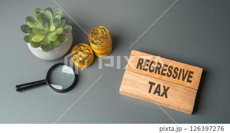 Regressive tax concept. Tax system where the tax rate decreases as the taxpayer's income increases, placing a heavier burden on low-income earners. Inscription on wooden blocks and coins Regressive tax concept. Tax system where the tax rate decreases as the taxpayer's income increases, placing a heavier burden on low-income earners. Inscription on wooden blocks and coins 126397276
