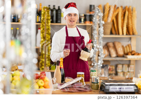 Young salesman is offering products for New Year party in grocery store Young salesman is offering products for New Year party in grocery store 126397364