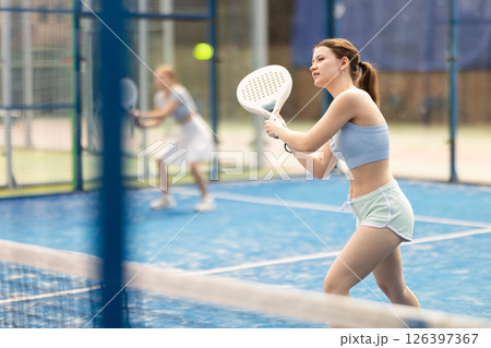 Young woman playing doubles padel tennis 126397367