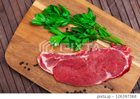 Piece of raw boneless beef with seasonings and greens Piece of raw boneless beef with seasonings and greens 126397368