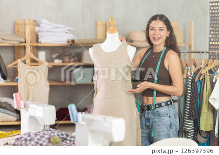 Female fashion designer sewing dress and testing it on mannequin Female fashion designer sewing dress and testing it on mannequin 126397396