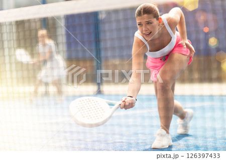 Woman with racket on court playing paddle in the background of sunshine Woman with racket on court playing paddle in the background of sunshine 126397433