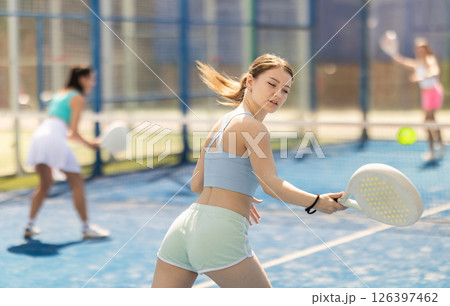 Young woman playing paddle tennis against team of women 126397462