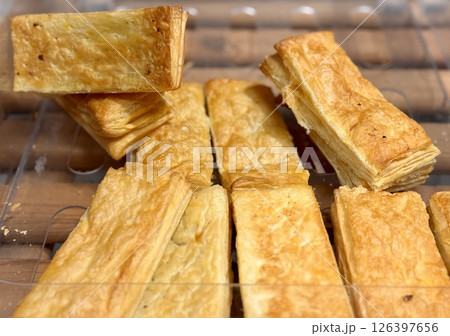 A closeup view of flaky, golden pastry snacks, which are ideal for finger appetizers or casual gatherings and events. A closeup view of flaky, golden pastry snacks, which are ideal for finger appetizers or casual gatherings and events. 126397656