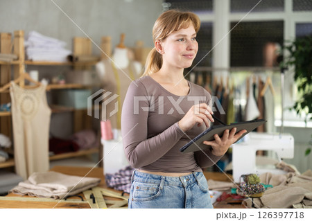 Female fashion designer drawing clothing on tablet in studio Female fashion designer drawing clothing on tablet in studio 126397718