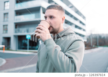 Man with beard hand holding paper coffee cup going walk outside on city street Man with beard hand holding paper coffee cup going walk outside on city street 126397814