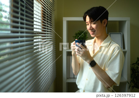 Relaxed man enjoying coffee by the window at home 126397912