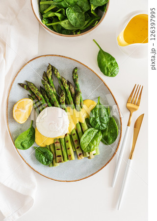 Poached egg with grilled asparagus, spinach, and hollandaise sauce on white table. Top view Poached egg with grilled asparagus, spinach, and hollandaise sauce on white table. Top view 126397995