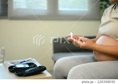 Close up of pregnant woman checking her blood sugar at home 126398030