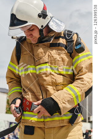 A firefighter dons the essential components of their professional gear, embodying resilience, commitment, and readiness as they gear up for a hazardous firefighting mission, a testament to their 126399538