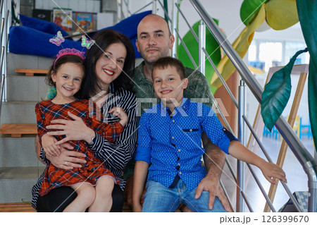 Portrait of a happy family. Photo of parents with children in a modern preschool classroom. Selective focus Portrait of a happy family. Photo of parents with children in a modern preschool classroom. Selective focus 126399670