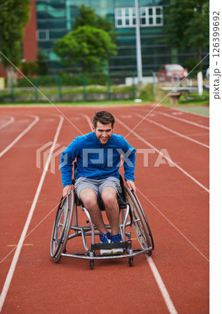 A person athlete with disability in a wheelchair racing on an outdoor track. A person athlete with disability in a wheelchair racing on an outdoor track. 126399692
