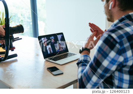 A freelancer sitting at a table in a modern living room, with headphones using a laptop for business video chat, conversation with friends and entertainment 126400123