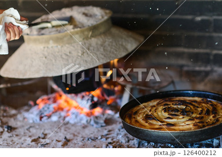 Capturing the essence of Bosnian culinary tradition, step-by-step preparation of a traditional Bosnian pie, showcasing the meticulous craftsmanship and authentic flavors involved in the culinary 126400212