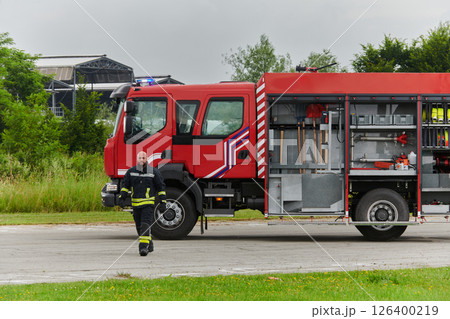 A firefighter meticulously prepares a modern firetruck for a mission to evacuate and respond to dangerous situations, showcasing the utmost dedication to safety and readiness in the face of a fire A firefighter meticulously prepares a modern firetruck for a mission to evacuate and respond to dangerous situations, showcasing the utmost dedication to safety and readiness in the face of a fire 126400219