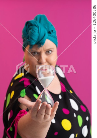 Stylish Woman Holding Hourglass Against Pink Background 126400386