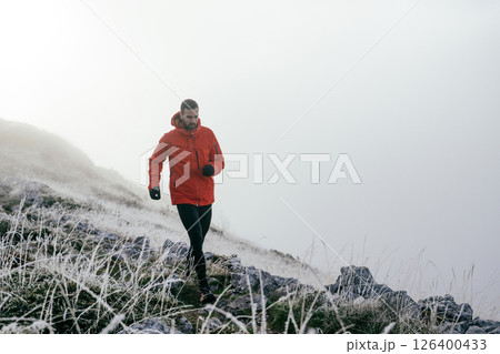 Man Climbing Rocky Hill in Fog Man Climbing Rocky Hill in Fog 126400433