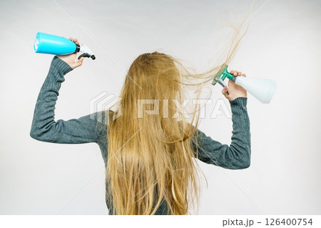 Female messy long hair holds spray bottle 126400754