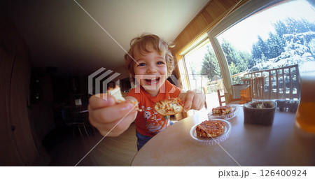Happy child enjoying a delicious snack in natural daylight, captured with a fish eye lens. Generated image 126400924