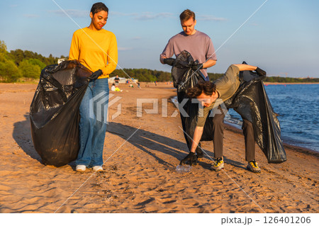 Earth day. Volunteers activists team collects garbage cleaning of beach coastal zone. Woman mans with trash in garbage bag on ocean shore. Environmental conservation coastal zone cleaning Earth day. Volunteers activists team collects garbage cleaning of beach coastal zone. Woman mans with trash in garbage bag on ocean shore. Environmental conservation coastal zone cleaning 126401206