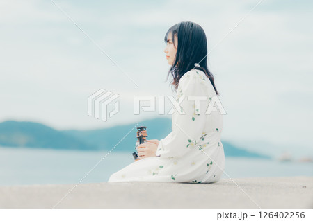穏やかな海辺で静かに佇む女性とランタン 穏やかな海辺で静かに佇む女性とランタン 126402256