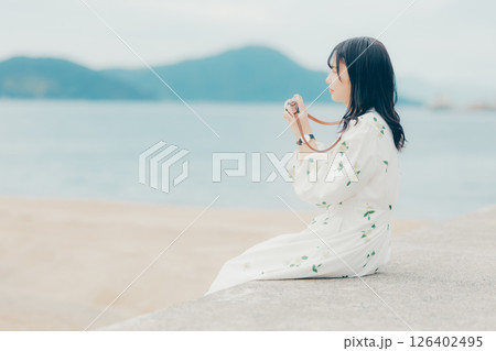 フィルムカメラを持つナチュラルな女性の横顔ポートレート 126402495