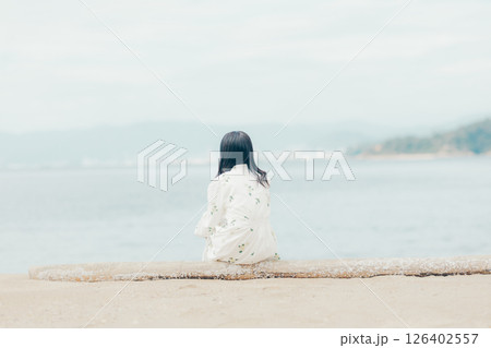 花柄ワンピースの女性が浜辺でスマートフォンを見る姿 126402557