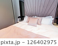 A cozy modern hotel bed with pastel pillows, elegant headboard and soft white bedding in a relaxing interior 126402975
