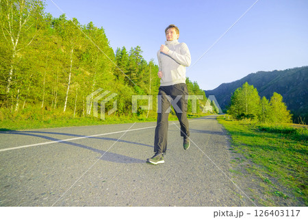 Man jogging in city partk at beautiful summer day. Sport fitness model caucasian ethnicity training outdoor. 126403117