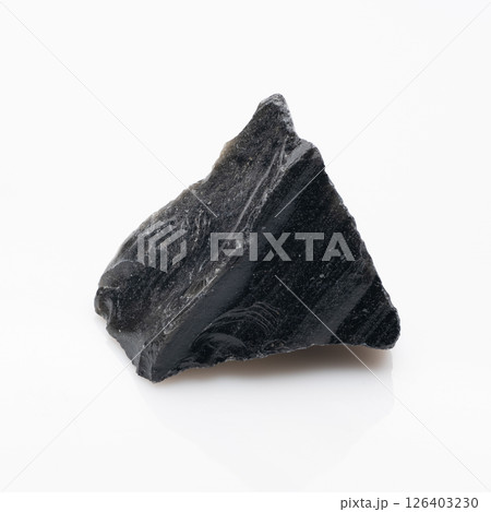 Raw Obsidian Rock Specimen on White Background: A Dark Volcanic Glass Formation with Reflective Surface and Rough Texture Displayed in Studio Lighting 126403230