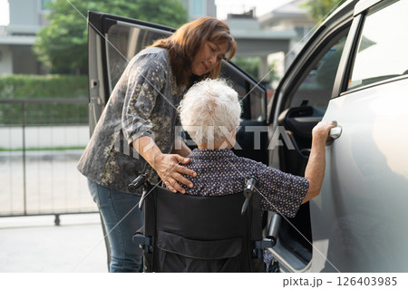 Caregiver help Asian elderly woman disability patient get in her car. 126403985