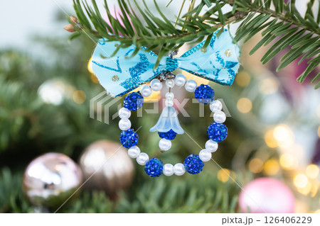 Handmade blue and white beaded christmas ornament hanging on pine tree branch 126406229