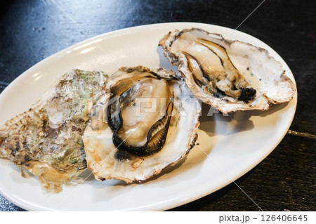 Close up of grilled raw oyster in three pieces on a white plate with copy space Close up of grilled raw oyster in three pieces on a white plate with copy space 126406645
