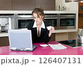 executive woman in kitchen with coffee looking at laptop computer	 126407131